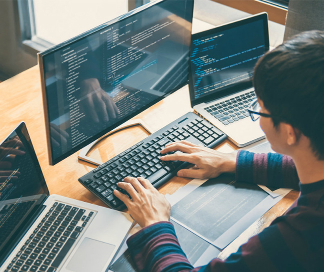 Man working through multiple laptops