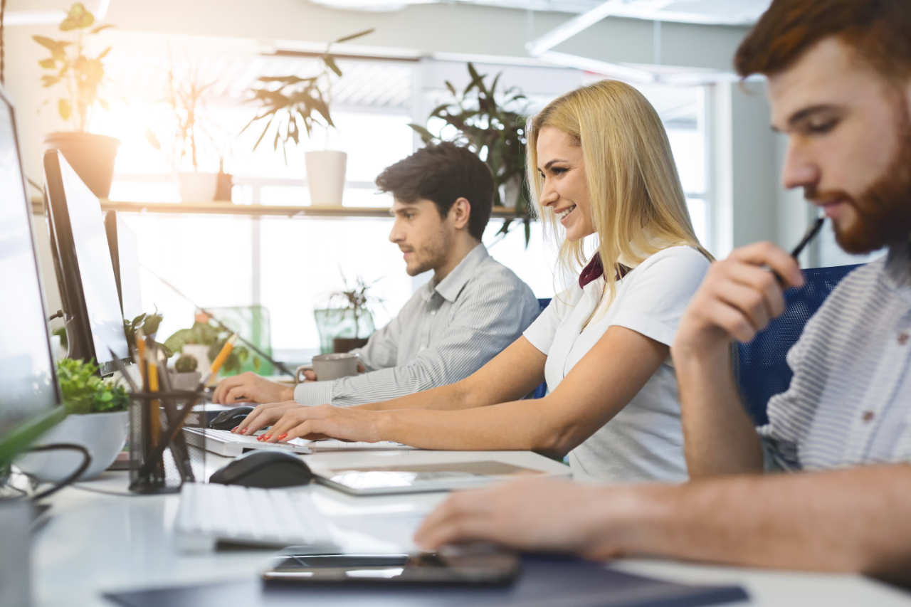 Diverse young people using office computers at coworking